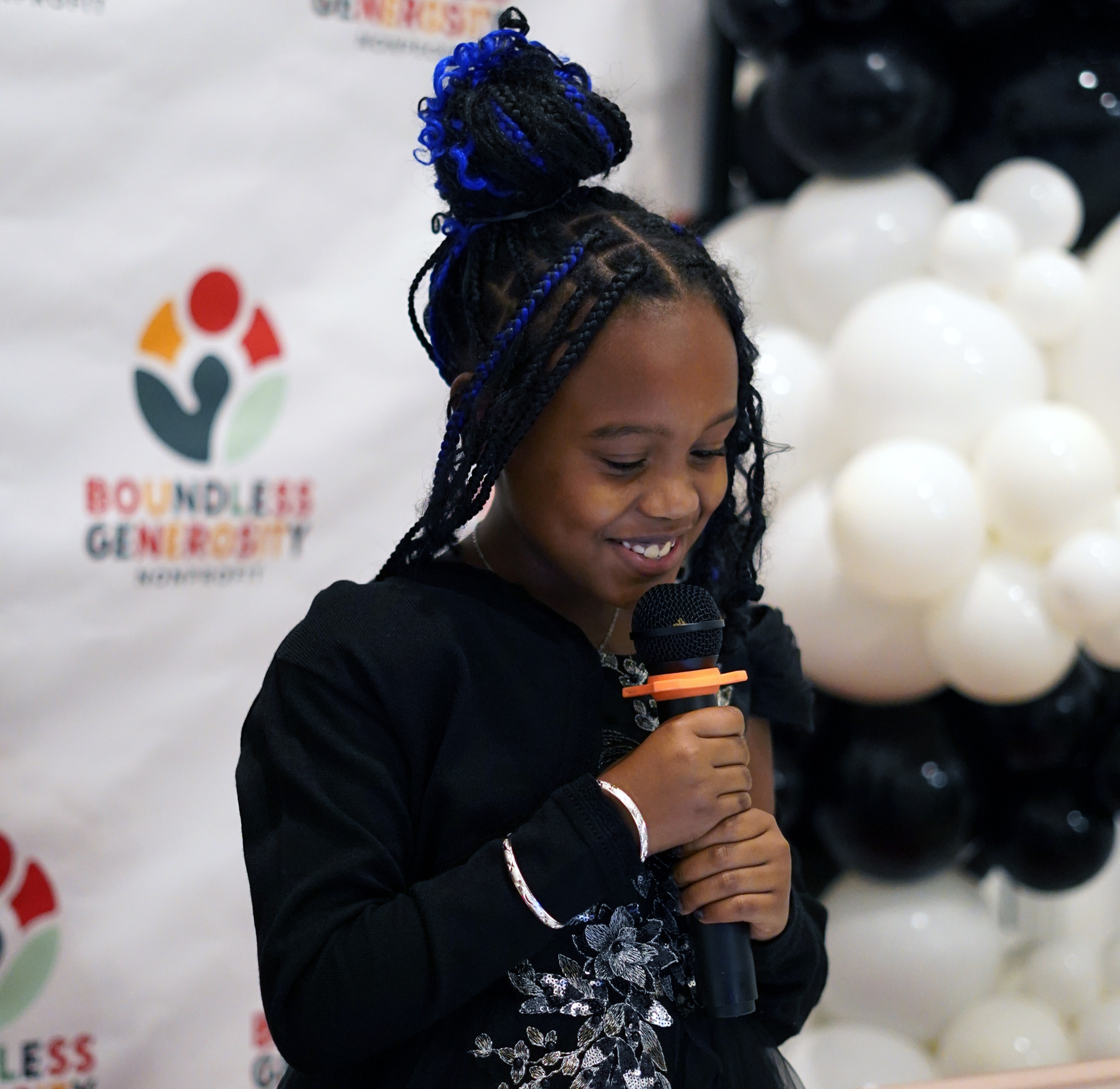 Savannah, young president of Boundless Generosity Corp, speaking at a microphone